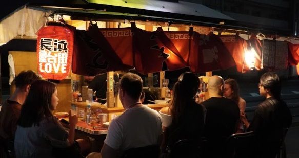 Builders sitting at a yatai food stall at night