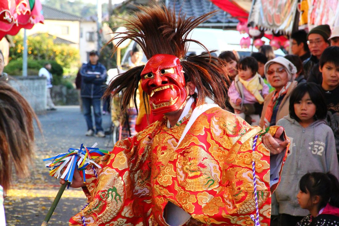 Kagura performer in a red oni mask and gold dragon kimono
