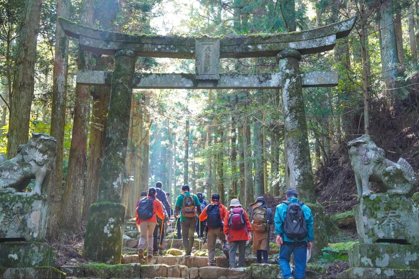 Moss-covered stone torii gate and komainu statues on the Mt. Kubote trail